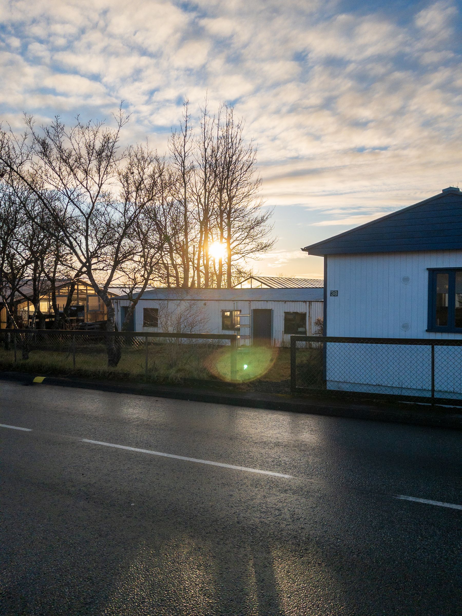 The sun peaks over a run down house. 