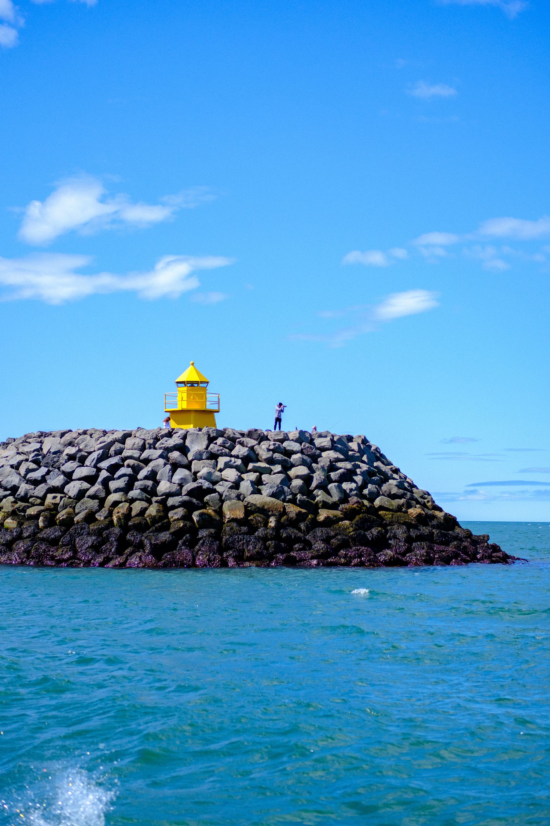 A photographer in Reykjavík harbour taking pictures of Viðey that's out off to the side.