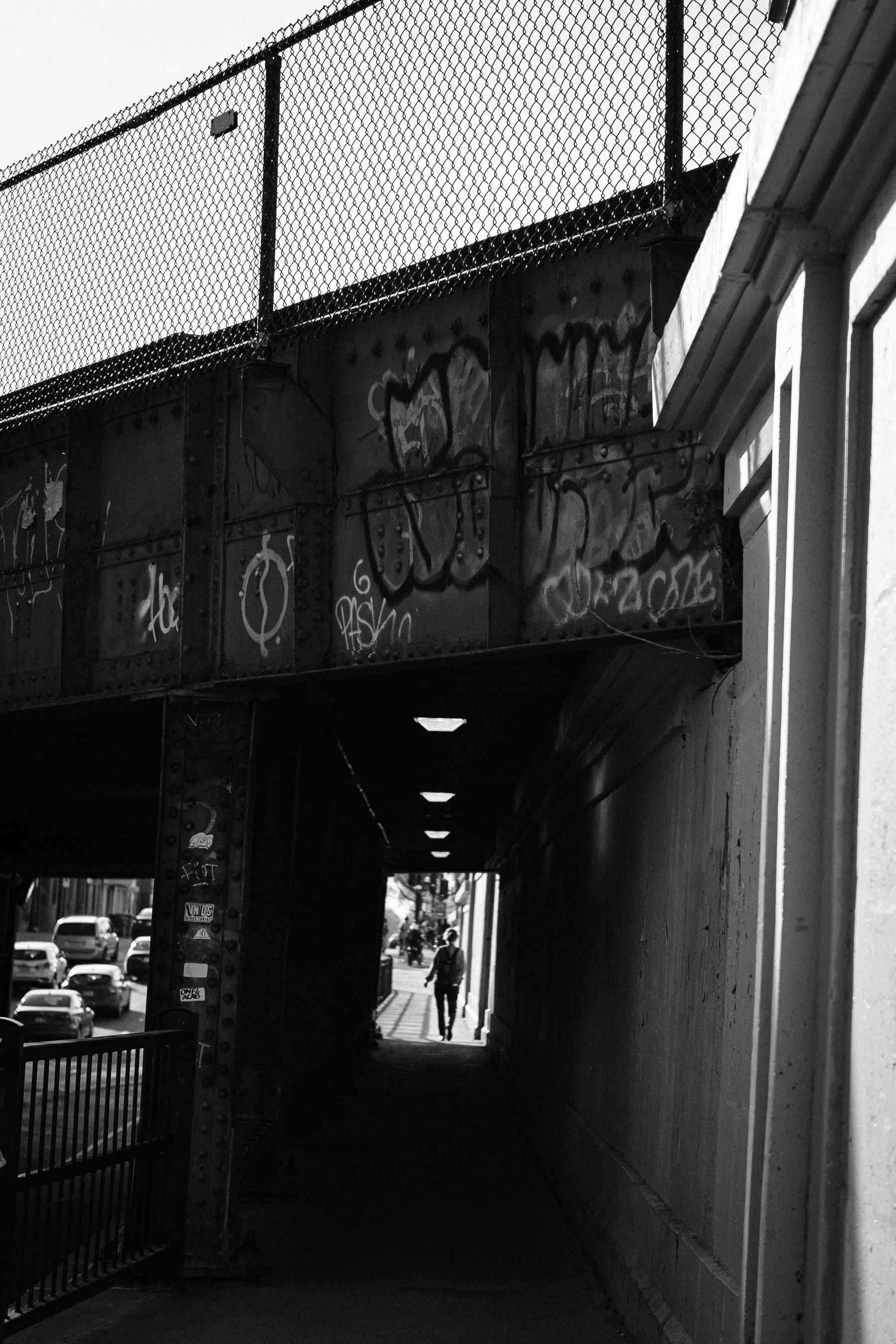 A view down the underpass under a railway bridge. We see the silhouette of a person on the other side