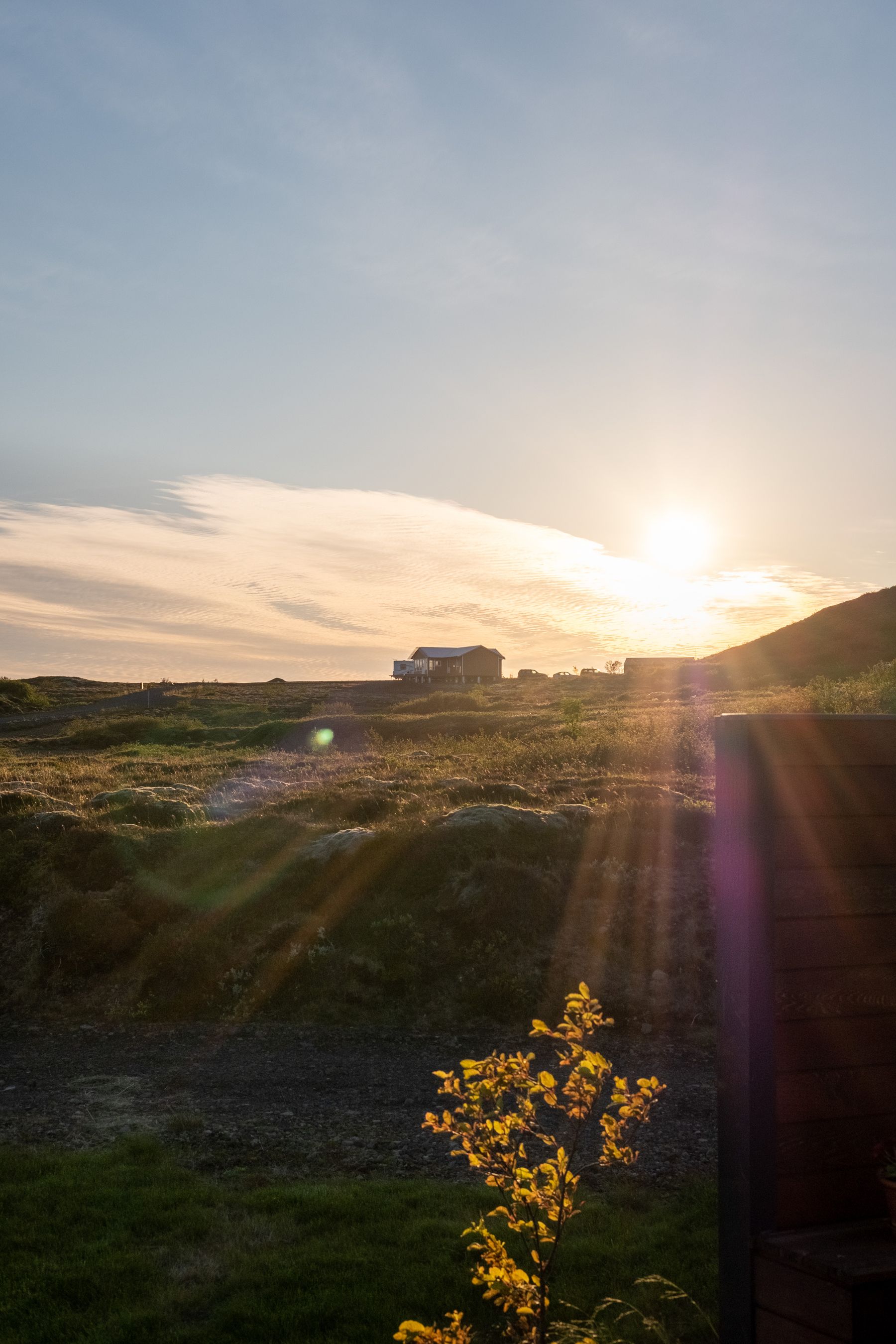 The sun is setting behind a summer cabin.