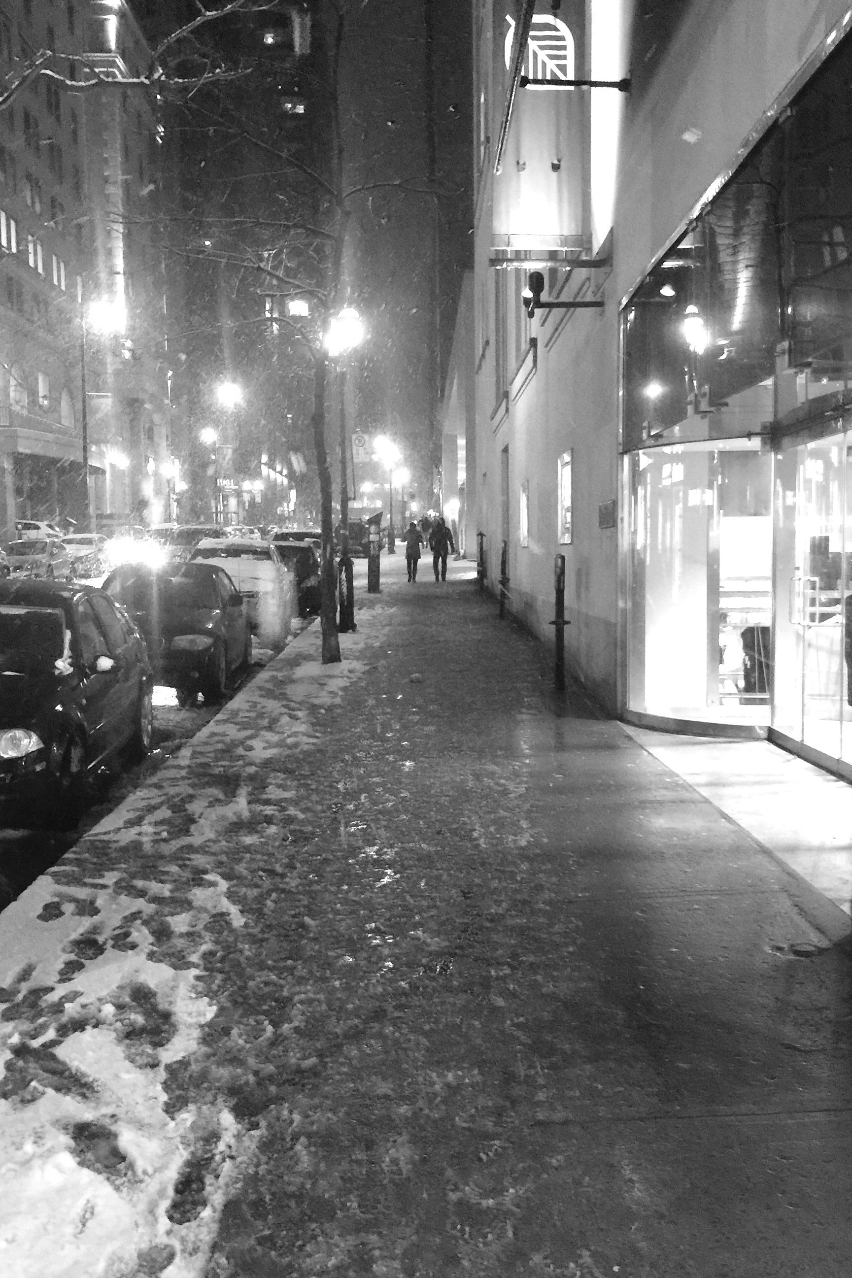 Ahead we see a couple walking along the sidewalk in a Montréal street.