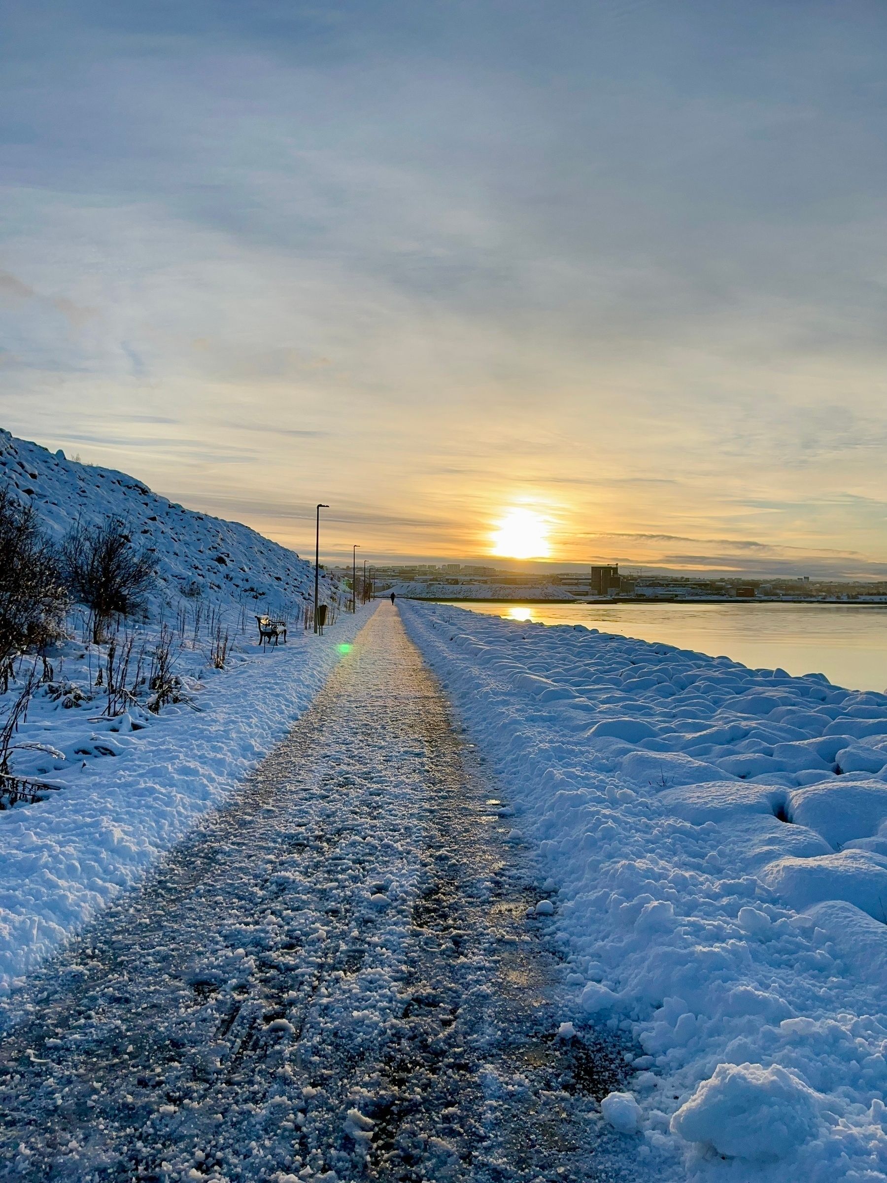 A walk along the ocean. Covered with snow. The sun is setting ahead.