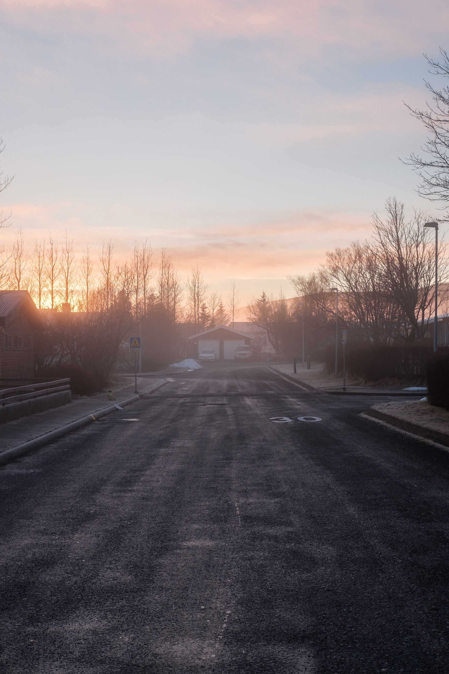 A frosty haze covers the neighbourhood road. 