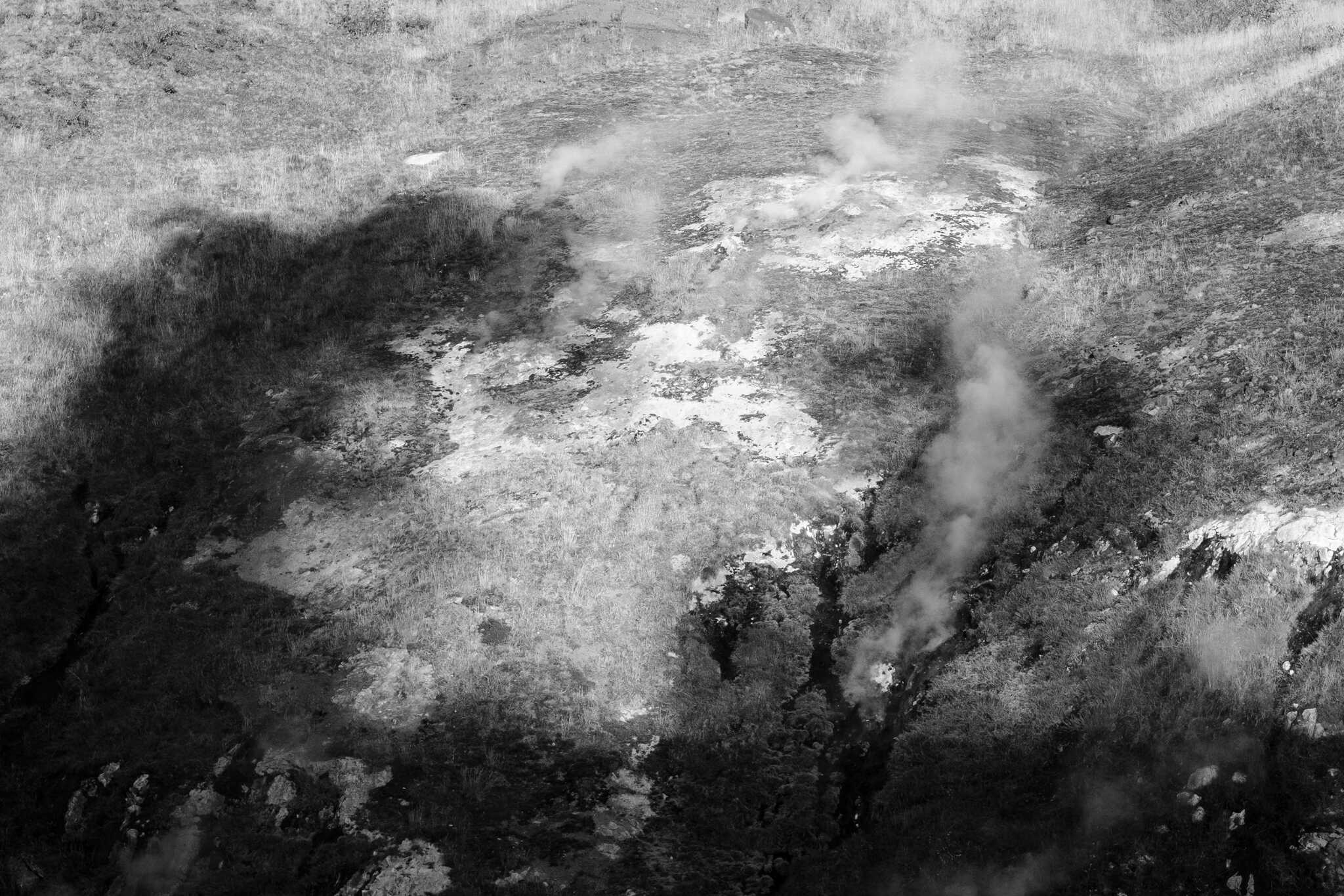 Large steam plumes cast dark shadows over a steaming hillside.