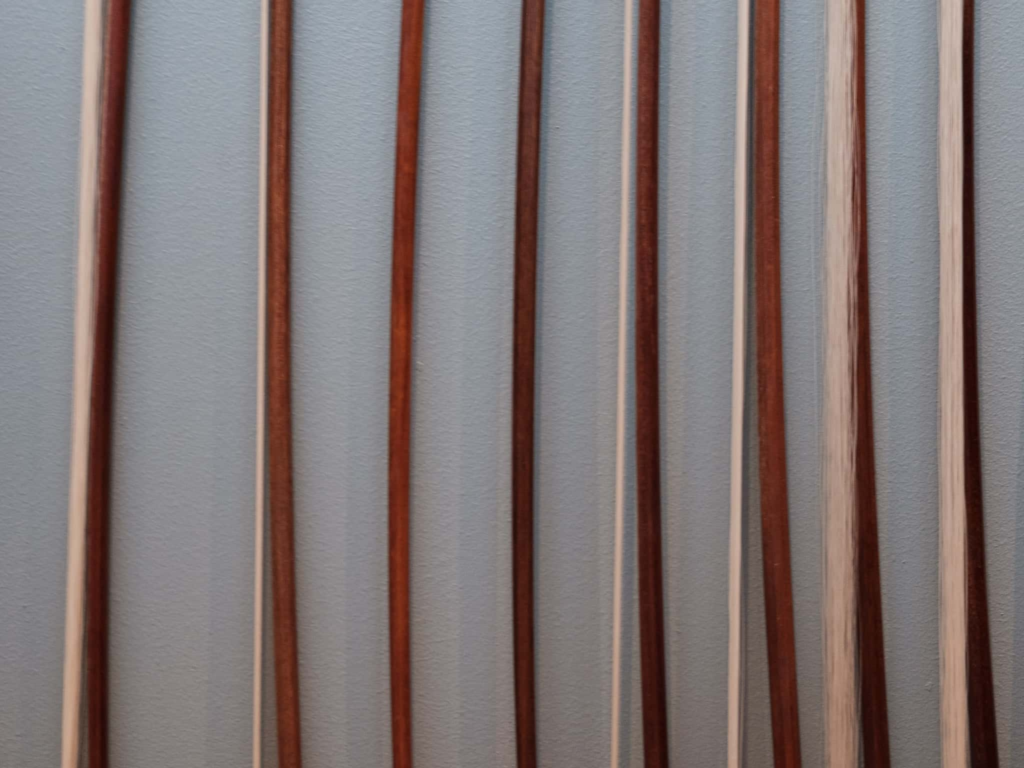 A cropped view of several violin bows on the wall.