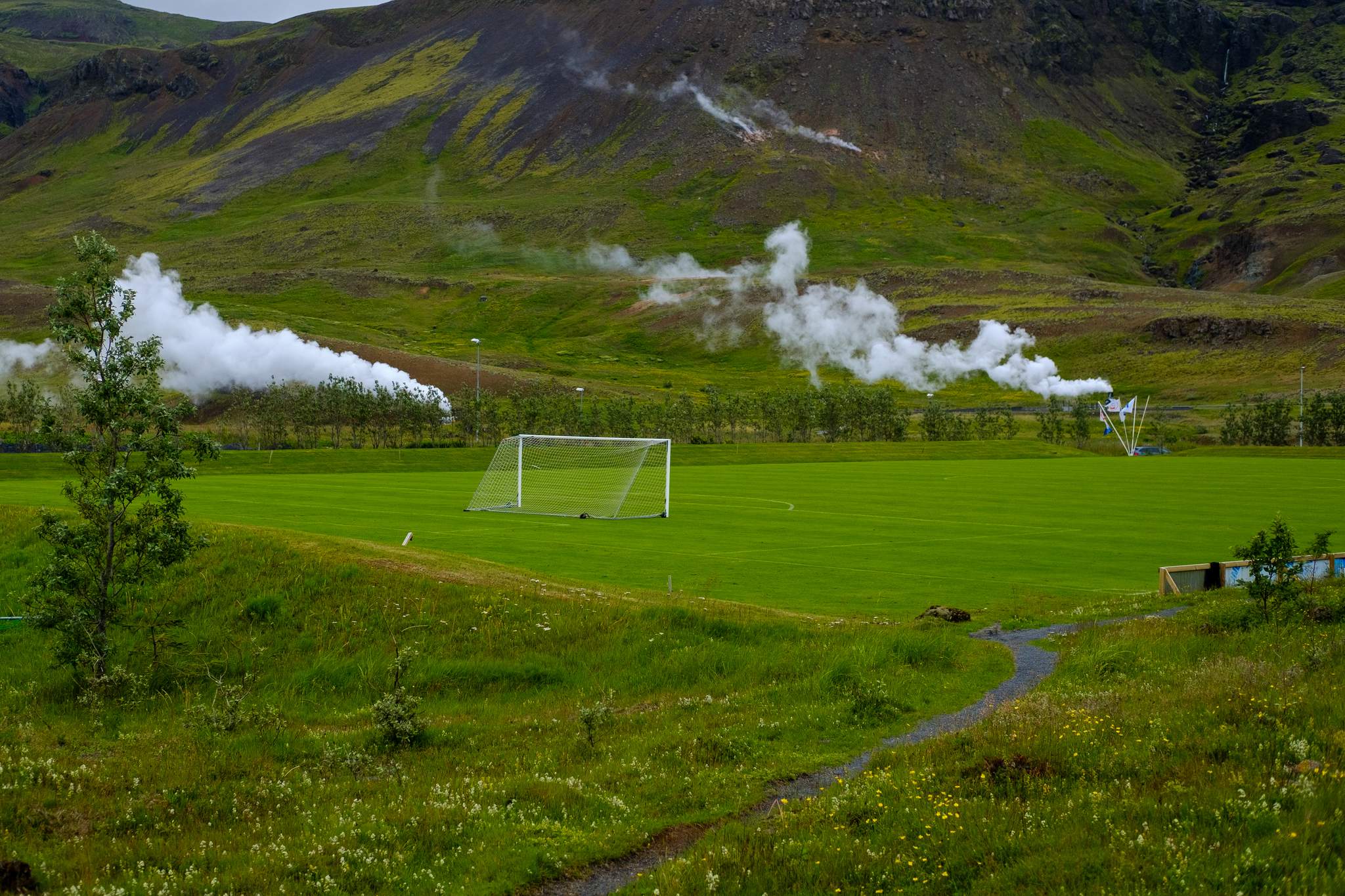 A football field. Behind it steam rises from geothermal wells.