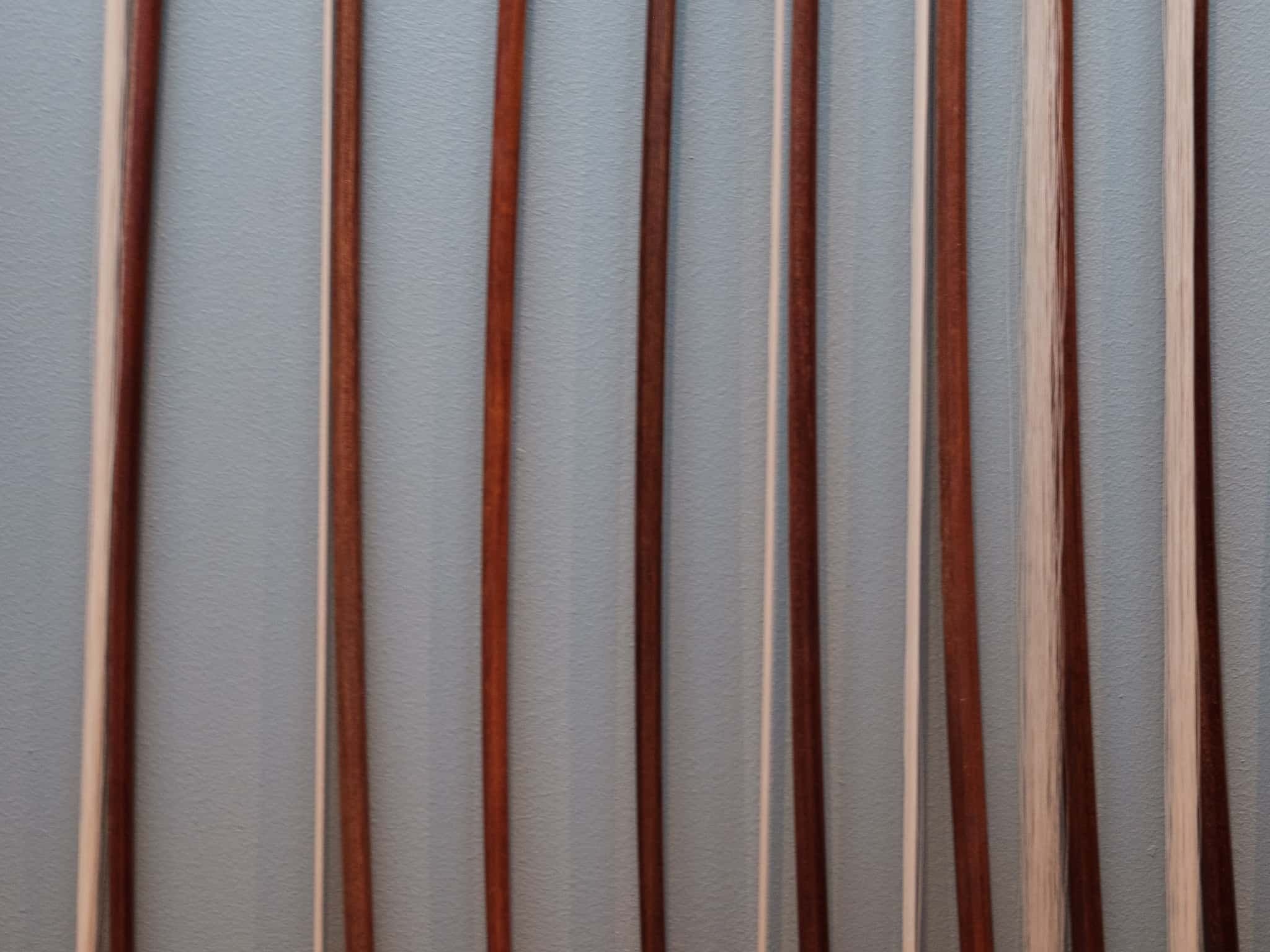 A cropped view of several violin bows on the wall.