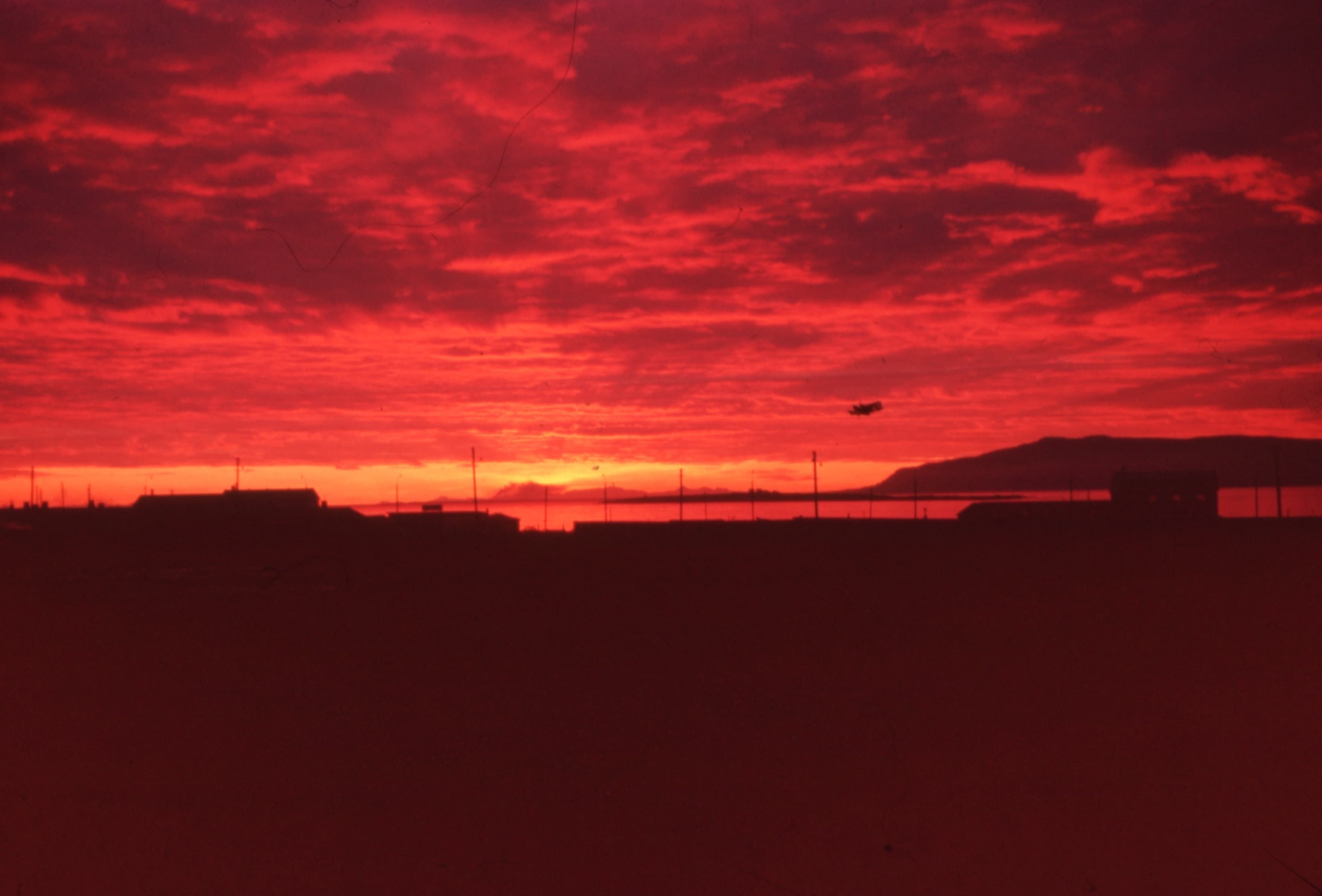 The view of a red-hued sunset over a fishing village